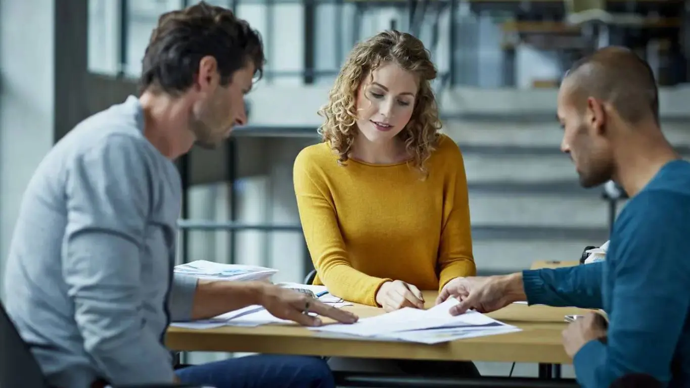 A man and woman sitting at a table with papers.